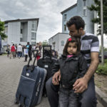 Vater und Tochter einer afghanischen Flüchtlingsfamilie sitzen erschöpft vor der Landesaufnahmestelle für Flüchtlinge (LASt) in Karlsruhe.