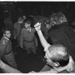 Öffnung der Mauer am 9. November 1989: während schon viele der Grenzübergänge von zwischen Ost- und Westberlin geöffnet wurden, ist der Grenzübergang "Friedrichstrasse" am Checkpoint Charlie immer noch geschlossen. Hinter dem Absperrtor stehen, wartend auf einen Befehl, unbeholfene Grenzbeamte.